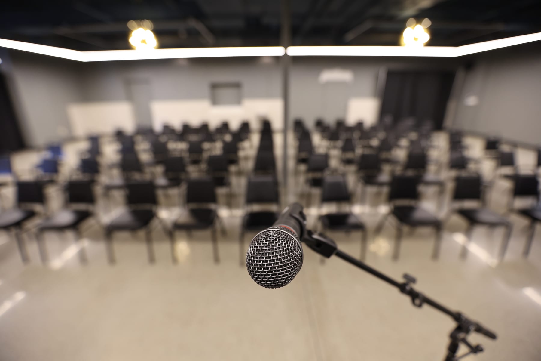 A microphone on its stand, the rows of chairs soft behind it